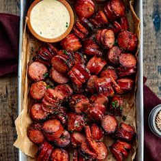 a tray filled with cooked sausages next to dipping sauce