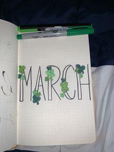 an open notebook with the word march written on it and shamrocks in black ink