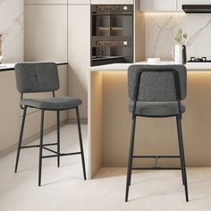 two gray chairs sitting next to each other in a kitchen with white counter tops and cabinets