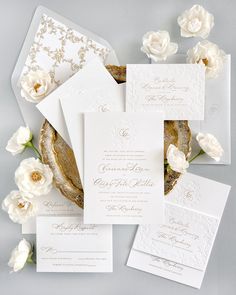 the wedding stationery is laid out on top of each other, with white flowers