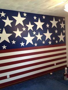 an american flag painted on the wall in a room with blue carpet and white walls