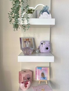 three white shelves with various items on them and a potted plant in the corner