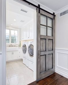 a washer and dryer in a white laundry room with an open barn door