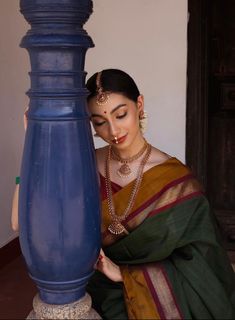 a woman in a sari leaning against a blue lamp