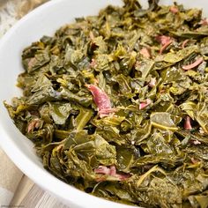 a white bowl filled with collard greens on top of a table