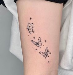 a woman's arm with three butterflies on it and stars in the sky above