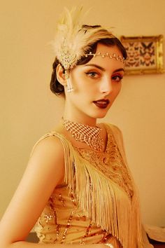 a woman wearing a feathered headpiece and pearls in her hair is posing for the camera