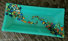 a green plate with colorful glass beads on it