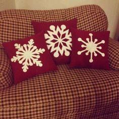 three red and white snowflake pillows sitting on a brown checkered sofa chair