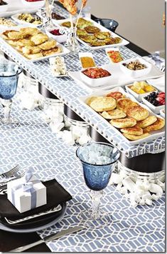 a table filled with lots of food on top of a blue and white table cloth