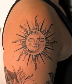 a sun and moon tattoo on the back of a woman's arm with flowers around it