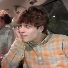 two young men sitting in the back seat of a car talking on their cell phones