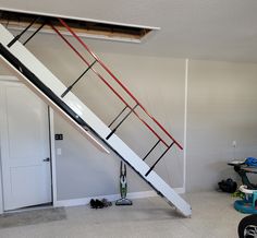 a white and red stair case in a garage with tools on the floor next to it