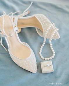 a pair of white shoes with pearls and a necklace on top of a blue blanket