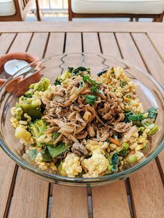 a glass bowl filled with food on top of a wooden table