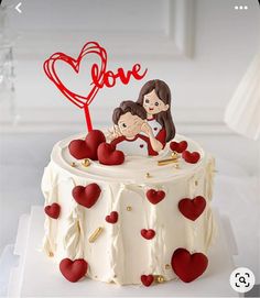 a cake decorated with hearts and a couple holding each other in the shape of a heart