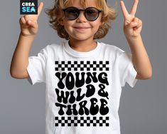 a little boy wearing sunglasses and holding up two fingers in front of his face with the words young wild & three written on it