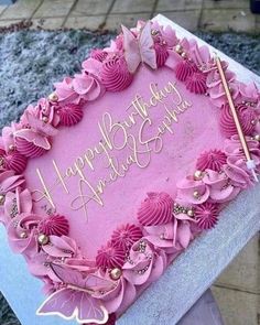 a pink birthday cake decorated with flowers and butterflies