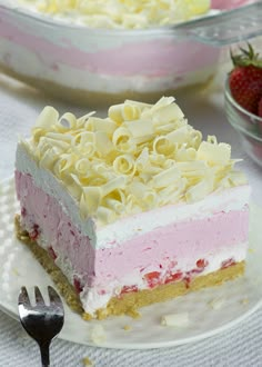 a piece of cake on a plate with a fork and bowl of strawberries in the background