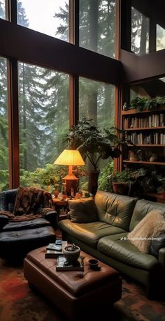 a living room filled with lots of furniture and large windows overlooking the trees in the distance