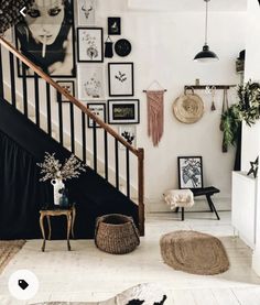 a living room with pictures on the wall and rugs in front of stairs leading to second floor