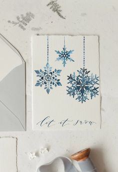 two snowflakes are hanging on the wall next to a pair of gloves and a card