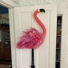 a pink flamingo standing on top of a white door