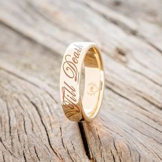 a gold wedding ring with the word god's love engraved on it sitting on a piece of wood