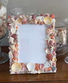 there is a frame made out of seashells on the table next to other shells