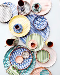 colorful plates and cups are arranged on a white surface