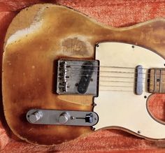 an old guitar is laying on a red carpeted surface and it's hard to tell