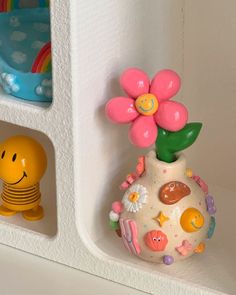 some toys are sitting on the shelf next to each other and one has a flower in it