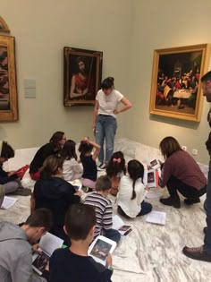 a group of people sitting on the ground in front of paintings