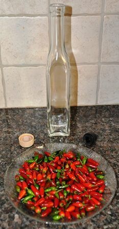 a bowl full of red peppers sitting on top of a counter next to a bottle