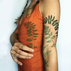 a woman with tattoos on her arm holding a cell phone and wearing an orange dress