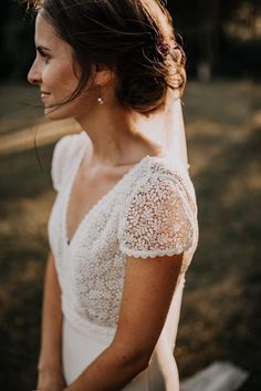 a woman wearing a wedding dress and veil in the sun with her hair pulled back