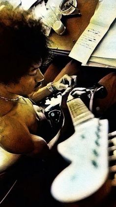 a young man sitting on top of a bed next to a guitar