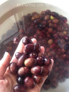 a person holding up some grapes in a bowl