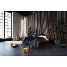 a bedroom with candles on the floor next to a bed and window curtained walls