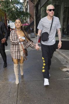 a man and woman walking down the street holding hands