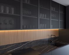 a kitchen with black cabinets and marble counter tops, along with glass shelves that have wine glasses on them