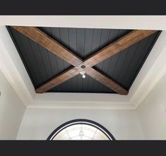 an arched window in the middle of a room with wood beams and a ceiling fan