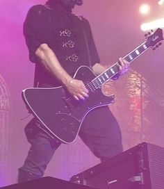 a man standing on top of a stage with a guitar in front of his face