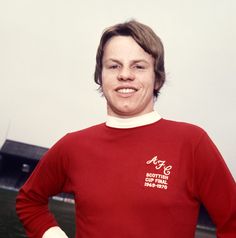 a woman in a red shirt is posing for the camera with her hands on her hips