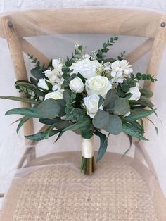 a bouquet of white flowers sitting on top of a wooden chair