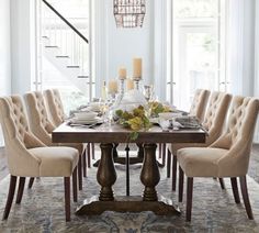 a dining room table with chairs and a chandelier hanging from the ceiling above it