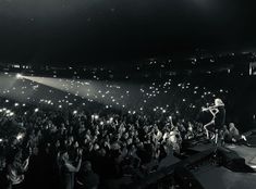 a black and white photo of a band performing on stage at a concert with people in the background