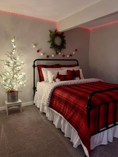 a bedroom decorated for christmas with red and white bedding, lights on the wall