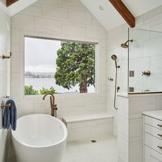 a large white bathtub sitting under a window next to a sink and shower faucet