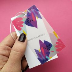 a woman's hand holding a card with flowers on it and a string attached to it